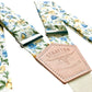 Close-up of cornflower blue and marigold floral button-on suspenders with Stratton Suspender Co. leather patch, handmade wedding accessories.