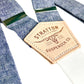 Close-up of Stratton Suspender Co.’s denim blue linen suspender straps with premium vegetable-tanned leather detailing. Featuring silver adjusters and a vintage-inspired leather patch, these handmade suspenders offer a refined alternative to clip-ons, ideal for weddings and formalwear.