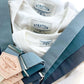 Groomsmen suspenders in popular wedding shades—dusty blue, teal, and slate—displayed over retro-inspired white shirts for vintage styling.