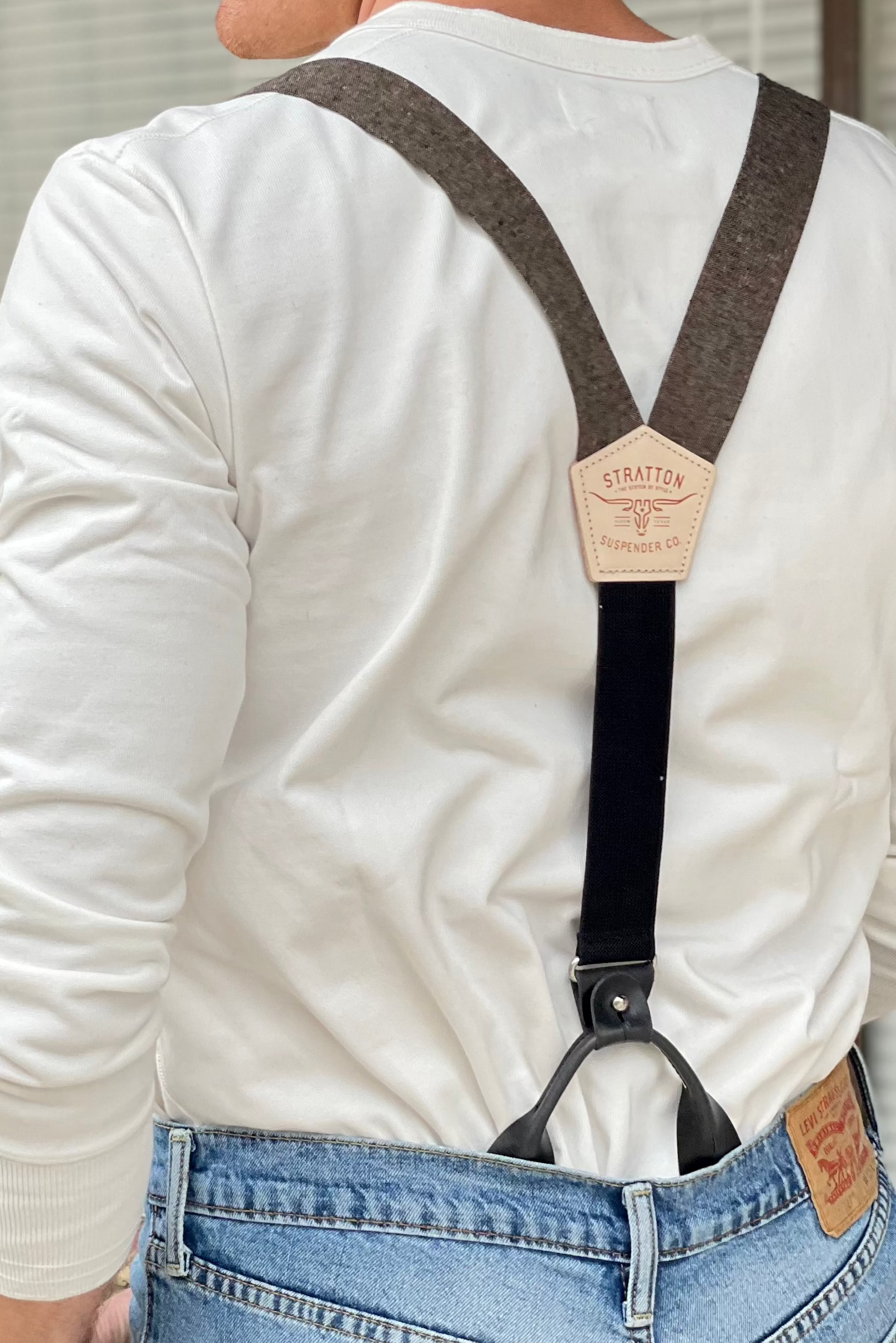Back view of espresso brown linen suspenders with black leather tabs, Y-back design, and Stratton Suspender Co. branded patch—worn with a vintage Henley shirt and classic denim for modern rustic groomswear or everyday menswear.