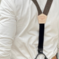 Back view of espresso brown linen suspenders with black leather button ends and Stratton patch, styled with a white Henley shirt and Levi’s jeans.