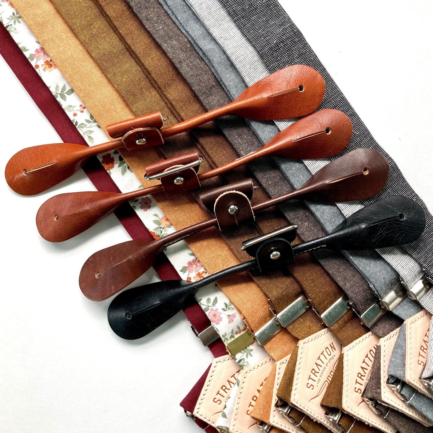 A variety of handmade button-on suspenders from Stratton Suspender Co. in rich fall tones—burgundy, floral, pecan, espresso, charcoal, and black—with matching leather button attachments, ideal for rustic weddings and groomsmen attire.