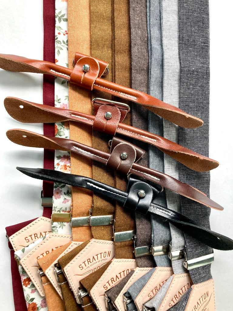 Close-up of Stratton Suspender Co. fall wedding suspenders in earthy linen tones with premium leather button-on attachments in tan, cognac, chocolate, and black—handmade men’s accessories for rustic weddings and vintage formalwear.