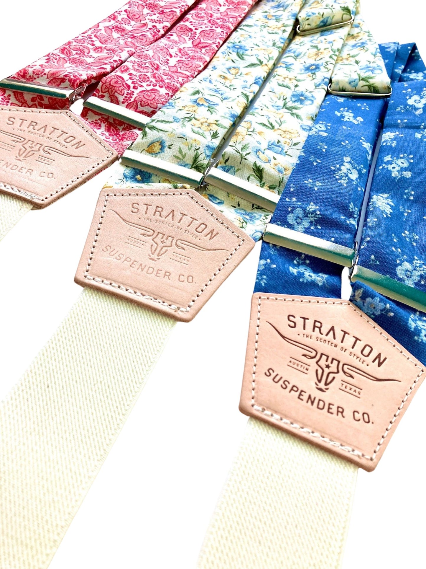 Close-up of Stratton Suspender Co. floral wedding suspenders in red, cornflower blue, and marigold patterns with full-grain leather patches