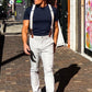 Man walking through The Domain in Austin, Texas, wearing ivory beige linen suspenders with chocolate brown leather attachments. Handmade vintage-style wedding braces paired with modern trousers and a navy shirt.
