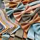 Close-up of fall linen wedding accessories including handmade bow ties, suspenders, and pocket squares in earthy pastel tones, ideal for groomsmen and rustic weddings.