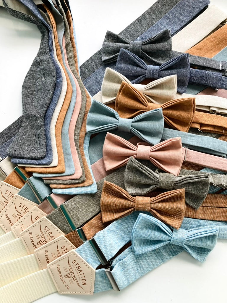 Assorted linen suspenders and matching bow ties from Stratton Suspender Co., featuring coordinated color sets for groomsmen, wedding parties, and formal menswear—handmade in Texas with classic and modern tones for rustic or vintage weddings.