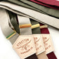 Neutral-toned linen suspenders for weddings, shown in burgundy, olive, and taupe with gold adjusters and leather detailing.
