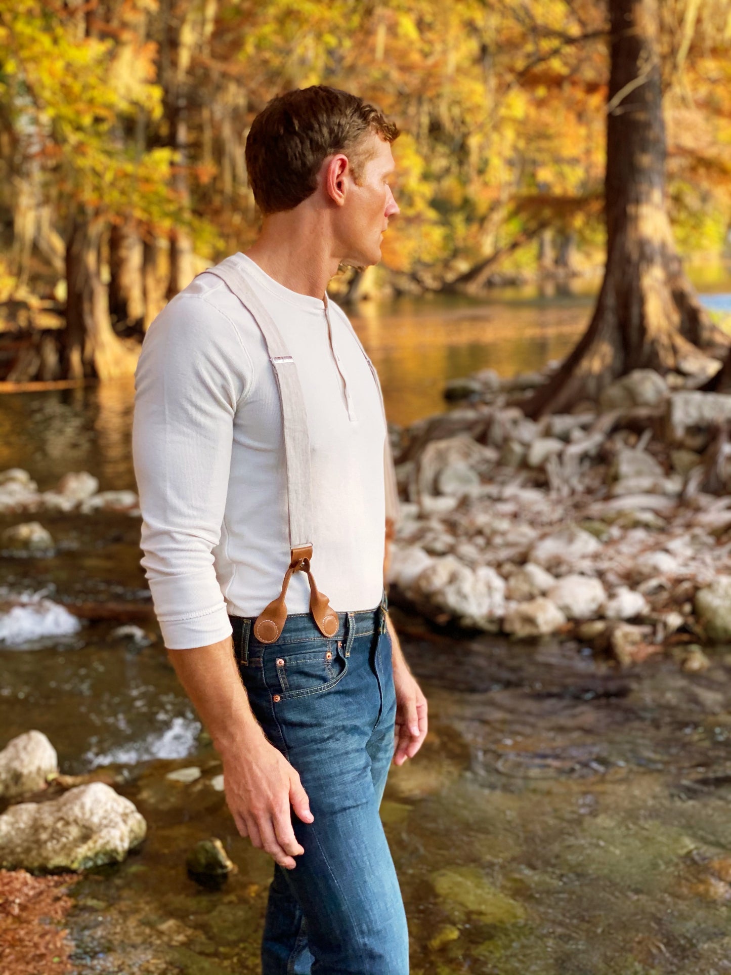 Man wearing Magnetic Clasp Suspenders with Beige Linen Straps, styled with a Henley shirt and denim in a rugged outdoor setting. A perfect blend of heritage craftsmanship and modern menswear.