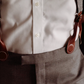 Close-up of magnetic clasp suspenders worn with a formal suit. Rich brown leather loops securely attach to waistband, offering a refined alternative to clip-ons. Perfect for weddings and formal menswear.