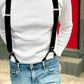 Close-up of monochrome black linen suspenders styled with a white textured long sleeve shirt and light blue jeans, featuring button-on leather tabs and silver hardware, handmade in Texas for classic menswear and weddings.