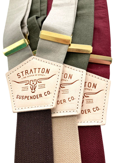 Earth-toned linen suspenders with Stratton leather patches and gold adjusters in taupe, green, and deep red.