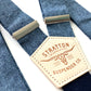 Close-up of Stratton Suspender Co. nautical blue linen suspenders with adjustable silver hardware and signature leather patch, ideal for rustic weddings or vintage groomswear.