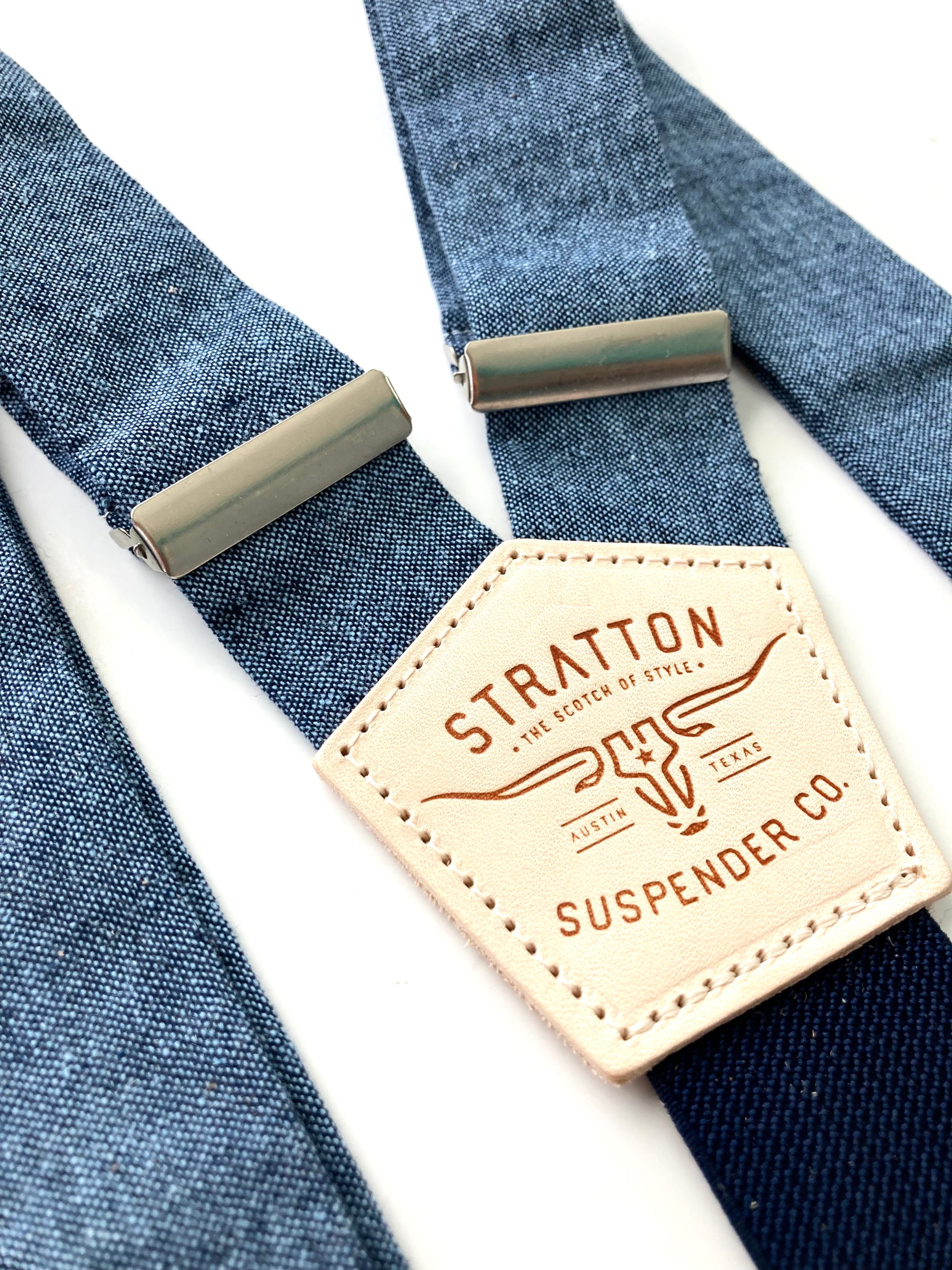 Close-up of Stratton Suspender Co. nautical blue linen suspenders with adjustable silver hardware and signature leather patch, ideal for rustic weddings or vintage groomswear.