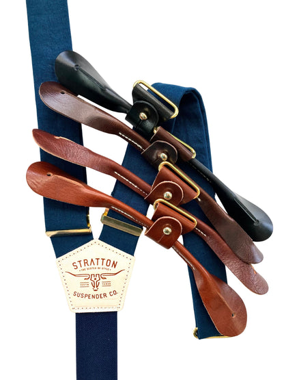 Navy and midnight blue suspenders with gold hardware, shown with four leather button tab options in black, chocolate, cognac, and tan.