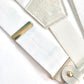 Close-up of pearl white linen suspenders with polished gold adjusters and leather button attachments, handcrafted for weddings, groomsmen, and formal menswear.