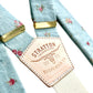 Close-up of powder blue vintage floral linen suspenders with gold hardware and Stratton Suspender Co. leather back patch, handmade in Texas for weddings and formal menswear.