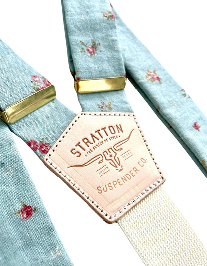 Close-up of powder blue vintage floral linen suspenders with gold hardware and Stratton Suspender Co. leather back patch, handmade in Texas for weddings and formal menswear.