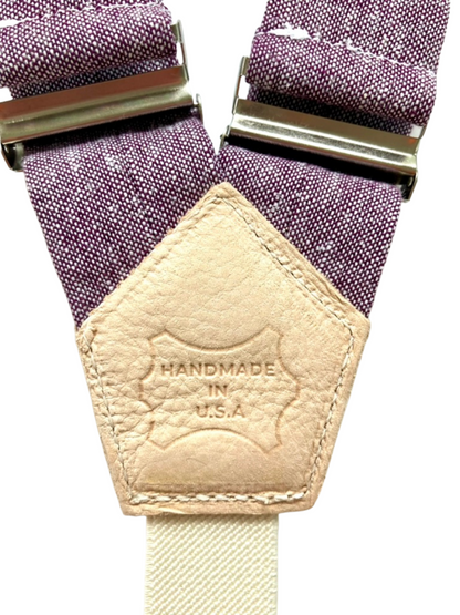 Close-up of genuine leather back patch on purple women’s suspenders with 'Handmade in U.S.A.' stamp, showcasing artisan craftsmanship.