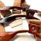 Close-up of roasted pecan brown hand-woven linen suspenders with tan and chestnut leather button-on attachments, featuring the Stratton Suspender Co. logo — ideal rustic wedding braces for grooms, groomsmen, and formal menswear.