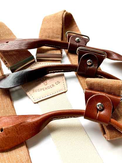 Close-up of roasted pecan brown hand-woven linen suspenders with tan and chestnut leather button-on attachments, featuring the Stratton Suspender Co. logo — ideal rustic wedding braces for grooms, groomsmen, and formal menswear.