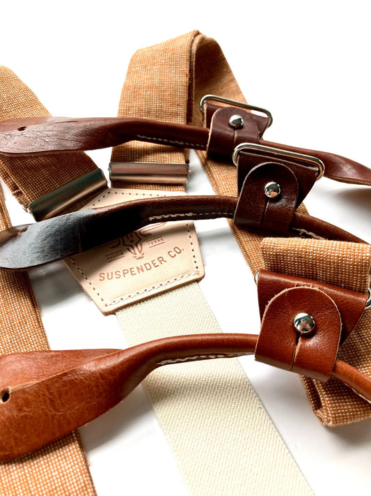 Close-up of roasted pecan brown hand-woven linen suspenders with tan and chestnut leather button-on attachments, featuring the Stratton Suspender Co. logo — ideal rustic wedding braces for grooms, groomsmen, and formal menswear.