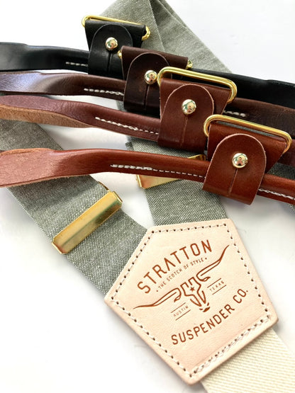 Sage green linen wedding suspenders with ivory elastic back strap, gold adjusters, and four leather button-on options in black, chocolate, cognac, and tan.