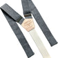 Flat lay of shale blue linen suspenders with cream elastic back strap, silver adjusters, and tan leather patch by Stratton Suspender Co., handmade in Texas for weddings and formalwear.