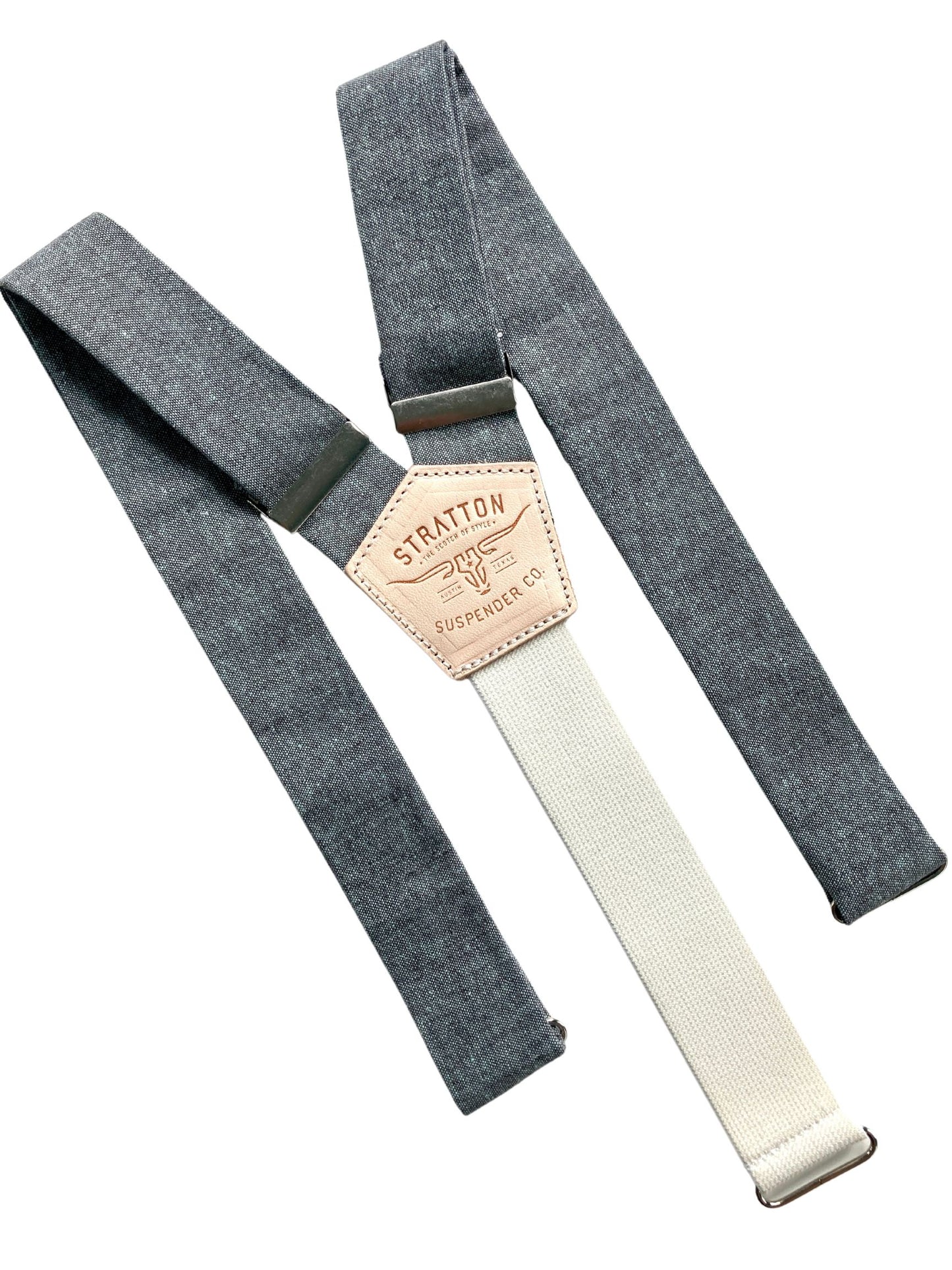 Flat lay of shale blue linen suspenders with cream elastic back strap, silver adjusters, and tan leather patch by Stratton Suspender Co., handmade in Texas for weddings and formalwear.