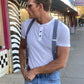 Man wearing Stratton Suspender Co denim blue linen suspenders with leather button-on ends and vintage white henley shirt, walking on South Congress in Austin, Texas.