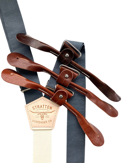 Slate blue linen button-on suspenders with brown leather tabs and vintage logo patch — handmade in USA, ideal for groomsmen or rustic weddings