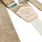 Close-up of tan linen suspenders with cream elastic back strap and Stratton Suspender Co patch, showcasing textured natural fabric and metal adjusters, handmade in Texas for weddings and classic menswear.