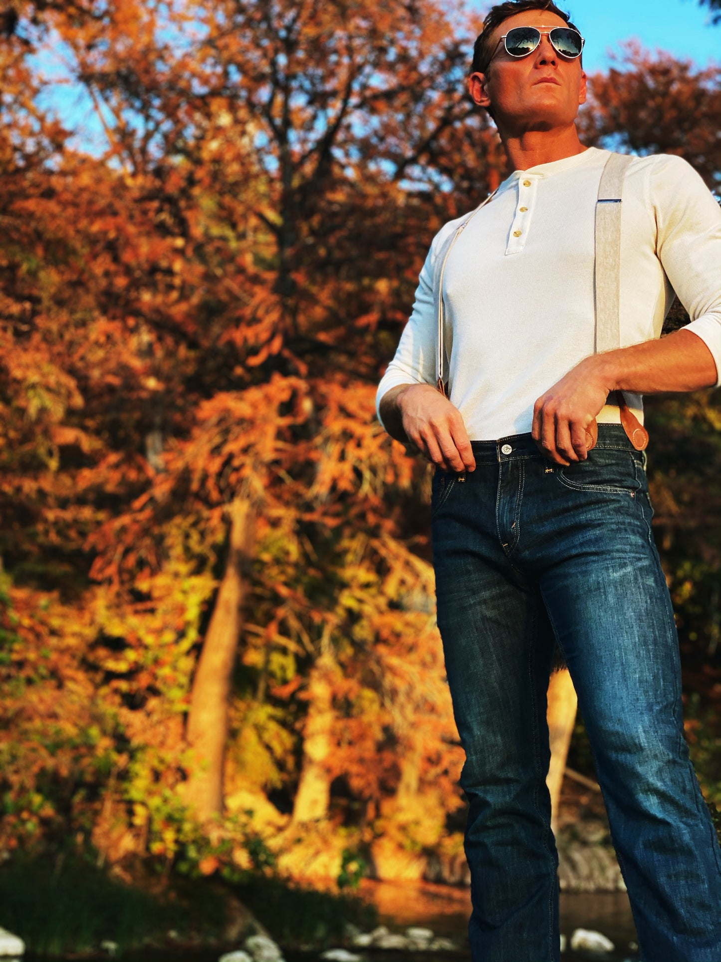 Man wearing Tan Magnetic Clasp Suspenders with Beige Linen Straps, styled with a Henley shirt and denim against a vibrant autumn backdrop. A rugged, heritage-inspired look for modern menswear.