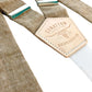 Detail shot of Stratton’s taupe linen suspenders with cream elastic back strap and branded leather patch, handmade in Texas for rustic groomsmen and formalwear styling.