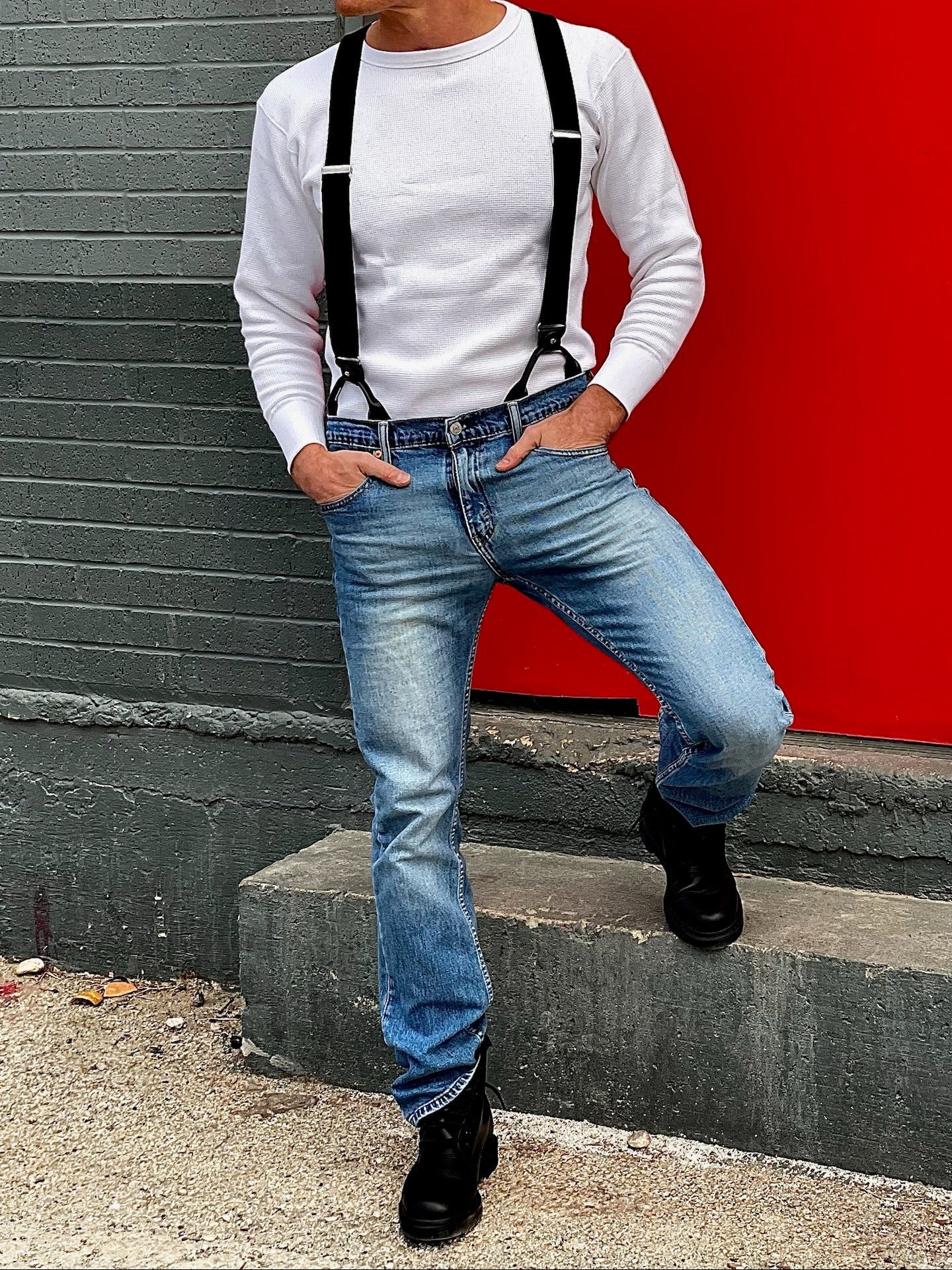 Man wearing a vintage-inspired white waffle knit thermal shirt paired with black suspenders, light-wash vintage Levi’s jeans, and black Dr. Martens boots. Ethically made in the USA, this heavyweight thermal is designed for warmth, durability, and classic American workwear style. Stratton Suspender Co.