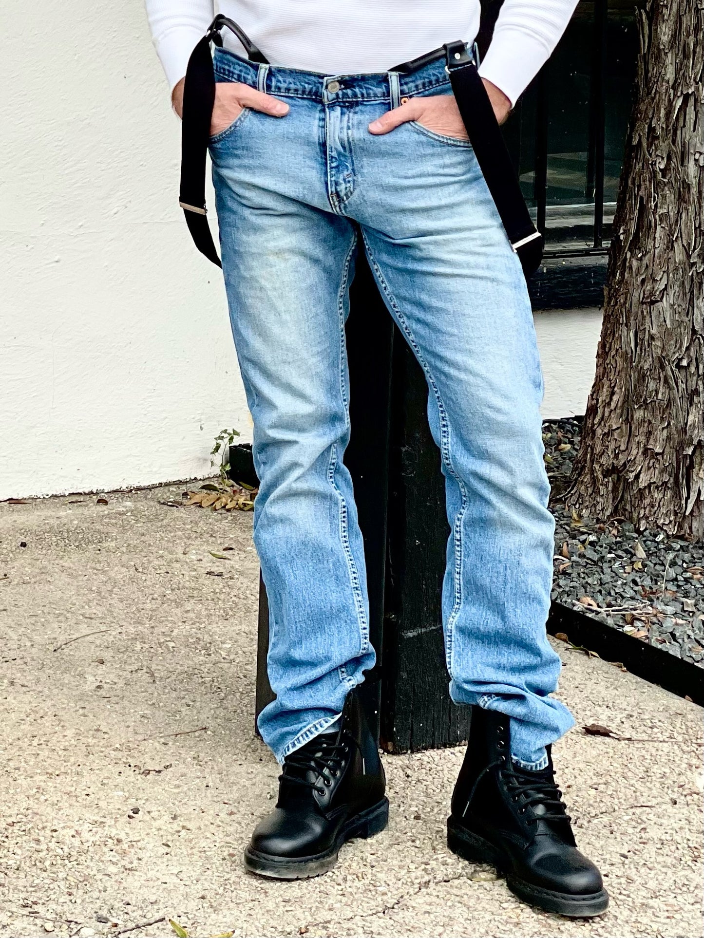 Man wearing black vintage button-on suspenders with light-wash jeans, a white ribbed shirt, and black leather boots. Handmade in Texas, USA – rugged and timeless fashion.