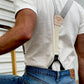 Back view of vintage charcoal beige suspenders with button-on leather attachments, worn with jeans and a white tee for classic menswear styling.