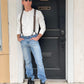 Man wearing a Vintage White Henley and brown wool suspenders by Stratton Suspender Co., standing confidently in front of a black door. Paired with denim and black boots, this rugged heritage menswear look embodies classic American workwear and craftsmanship.
