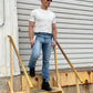 Man wearing a vintage 1940s heavyweight white t-shirt with gray linen suspenders by Stratton Suspender Co. Styled with classic denim and rugged black boots, he steps down a weathered industrial staircase, capturing timeless American workwear and heritage menswear in an authentic setting.