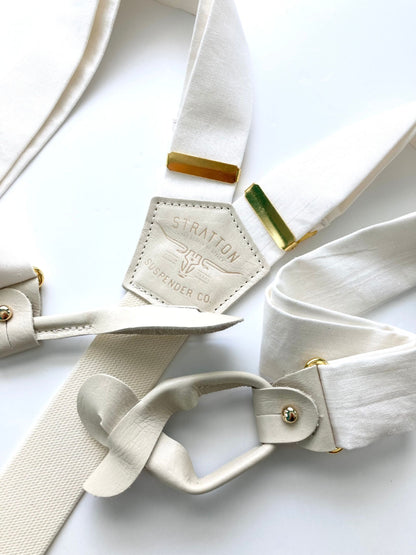 Close-up of white tuxedo button-on suspenders with gold brass hardware by Stratton Suspender Co., featuring leather button attachments and a vintage-inspired design—perfect for weddings, formal events, and classic menswear styling.