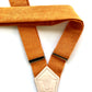 Back strap detail of women’s tangerine orange linen suspenders with cream elastic and embossed leather logo patch.