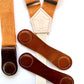 Women’s tangerine orange linen suspenders with interchangeable magnetic clasps in chocolate, cognac, and tan leather.
