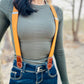 Women’s tangerine orange linen suspenders with tan magnetic clasps styled with high-waisted denim and fitted top.
