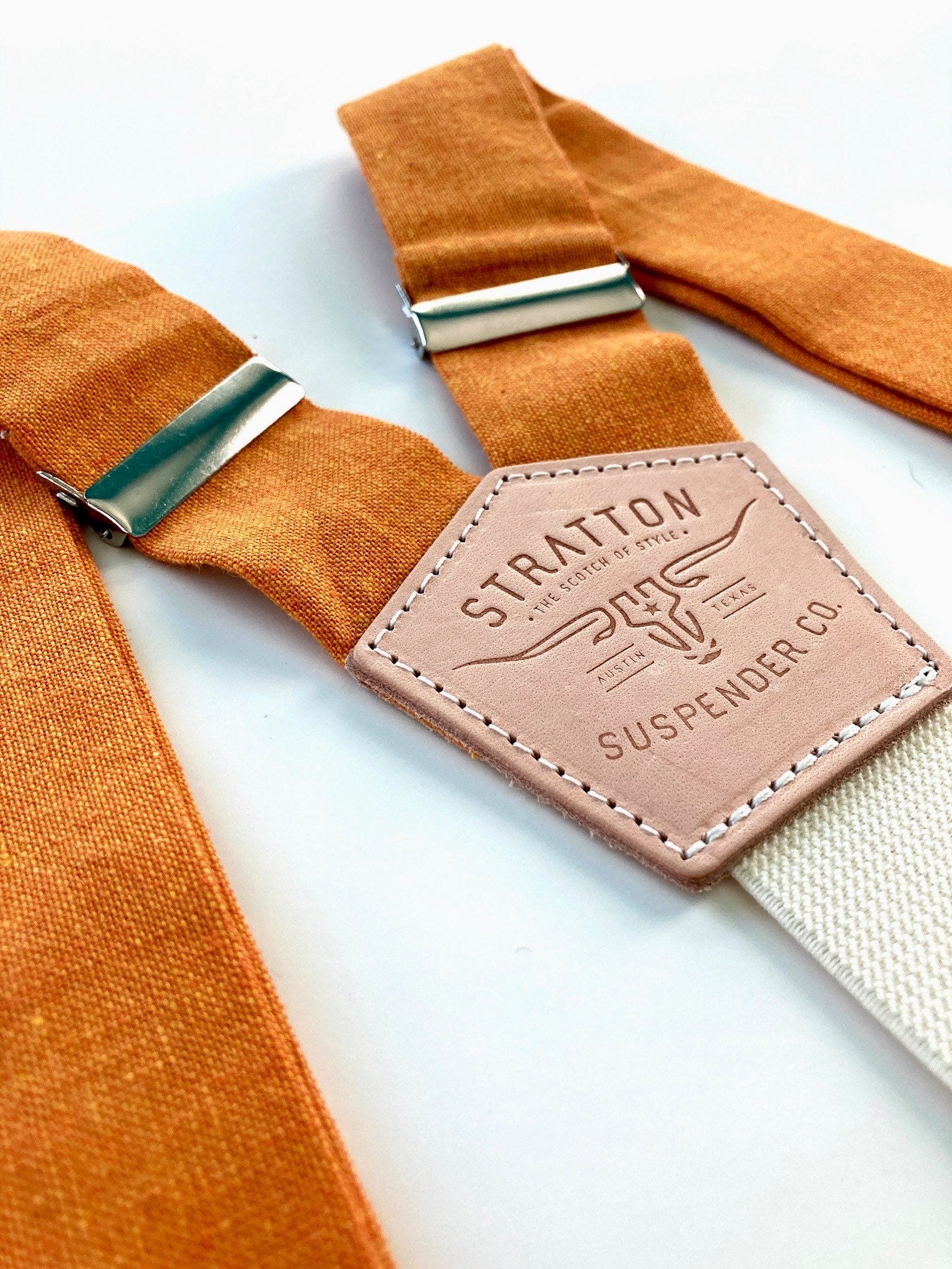 Stratton Suspender Co. features the orange linen suspenders on veg tan shoulder leather with cream colored elastic back strap for the Fall 2022 suspenders collection 